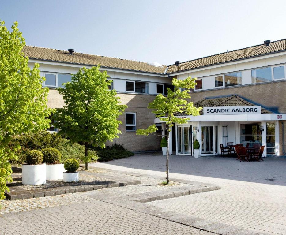 奥尔堡东奥尔堡斯堪迪克酒店的一座建筑,前方有种有树木的庭院