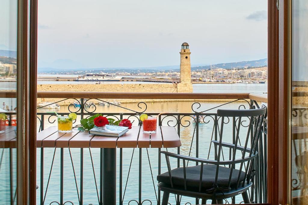 罗希姆诺Vista Del Porto Luxury Suites的阳台配有桌椅,享有水景