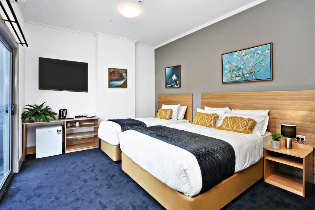 悉尼Meridian Hotel Hurstville的酒店客房设有一张大床和一台电视。