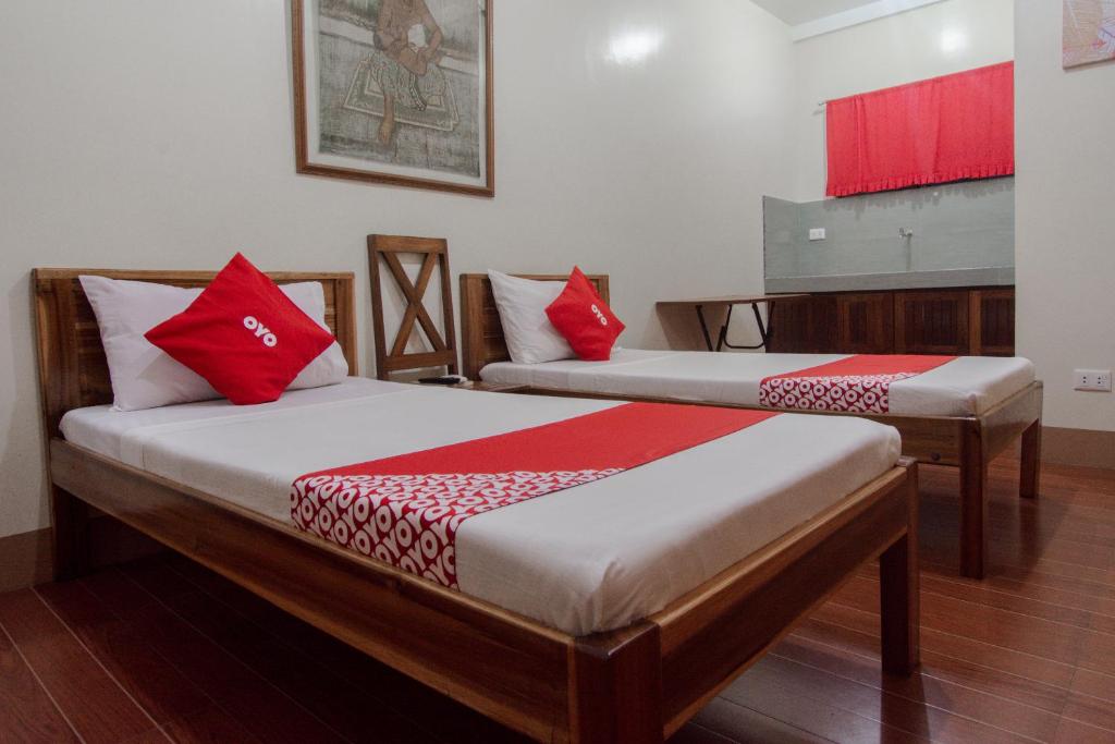 公主港OYO 658 Roccksar Pension的客房内的两张床和红色枕头