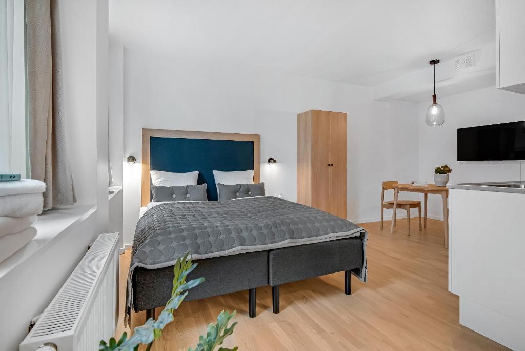 哥本哈根STUDIO1A Hotel Apartments的一间卧室配有一张床,厨房配有桌子