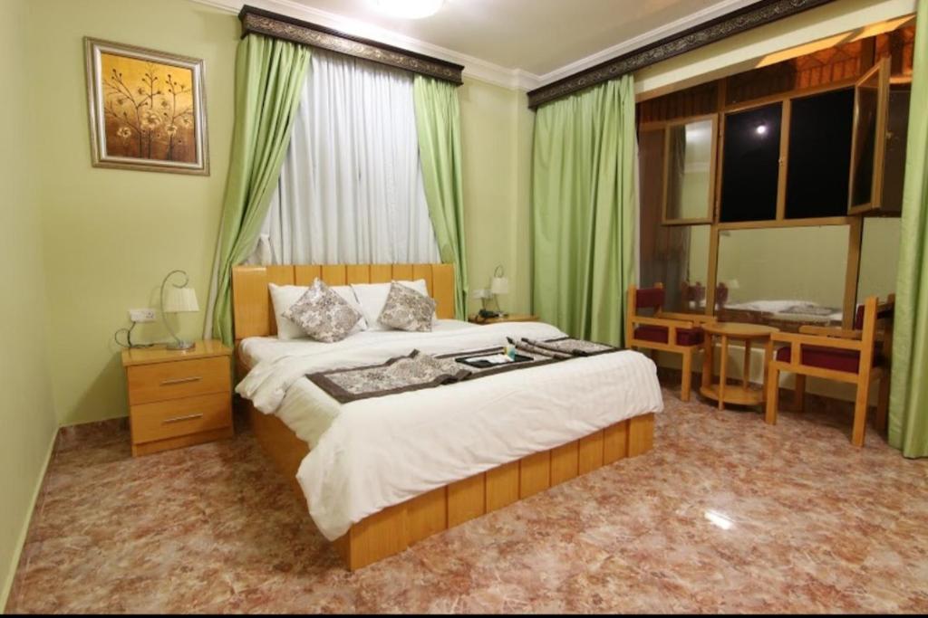 尼兹瓦DREAMLAND HOTEL APARTMENT NIZWA的一间卧室配有一张床、一张书桌和一个窗户。