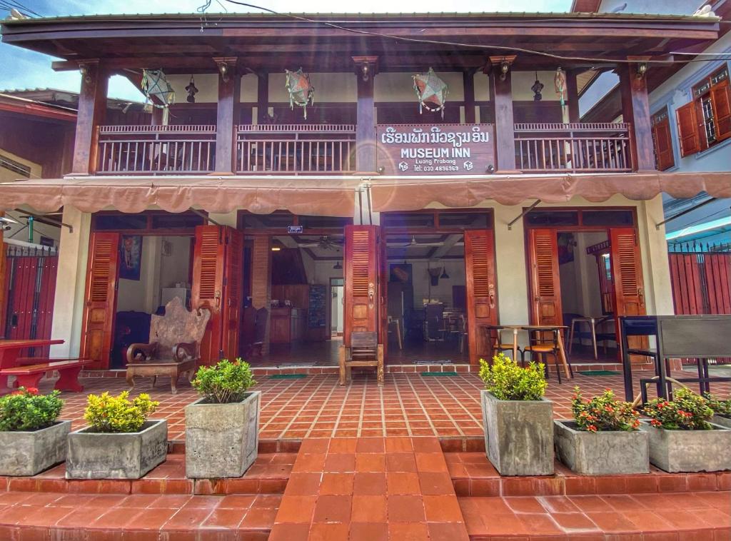 琅勃拉邦Luang Prabang Museum Inn & Travel的前面有盆植物的建筑