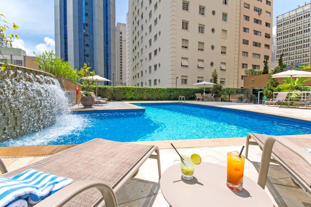圣保罗Transamerica Prime International Plaza (Paulista)的露台的游泳池配有桌子和饮料