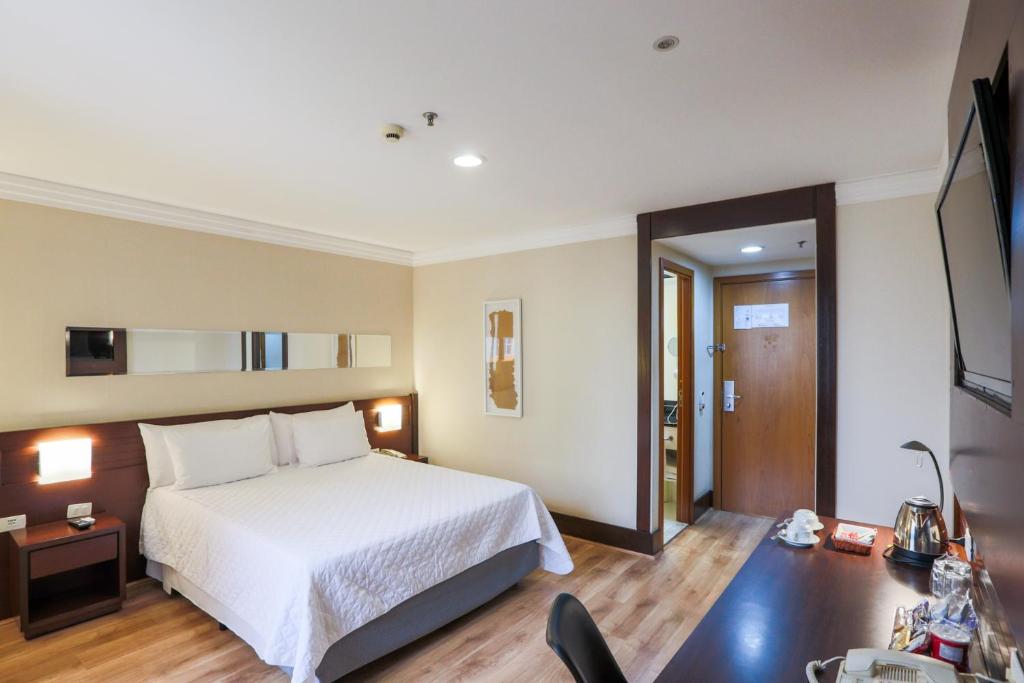 圣保罗泛美孔戈尼亚斯行政酒店的一间卧室配有一张床和一张桌子及椅子