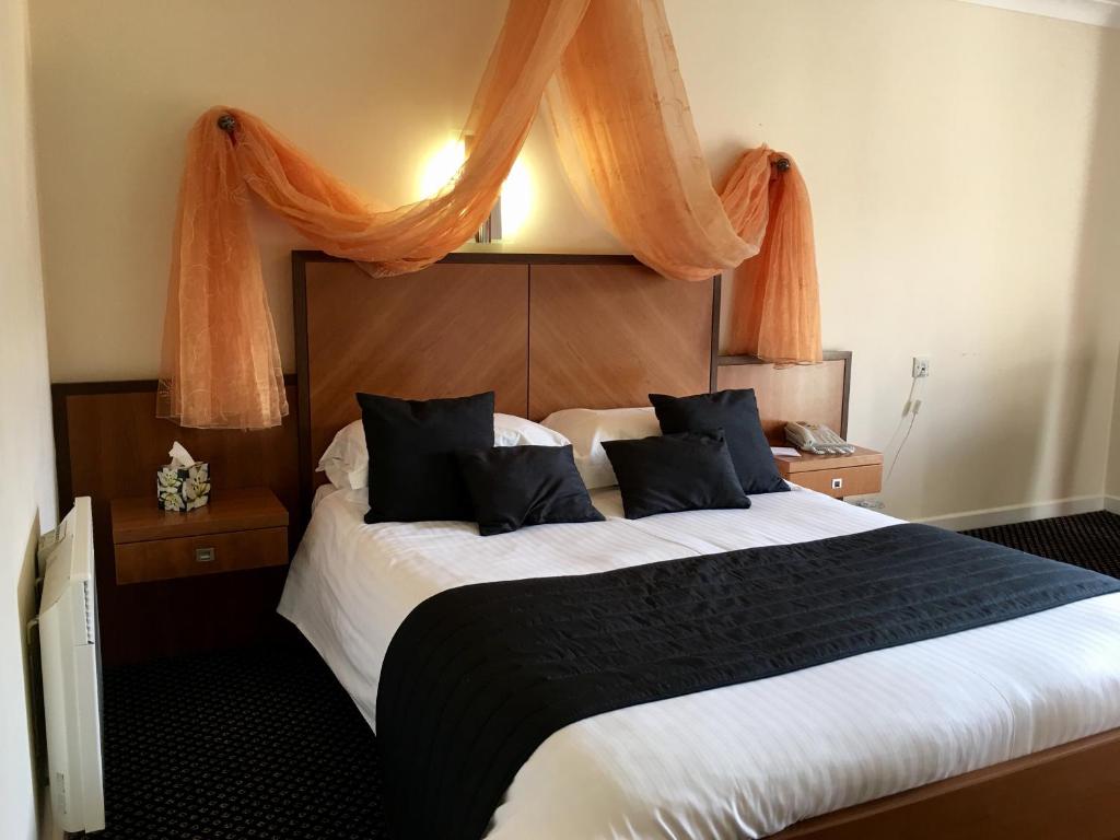 卡伦普顿帕德布罗克公园酒店的一间卧室配有带橙色窗帘的大床