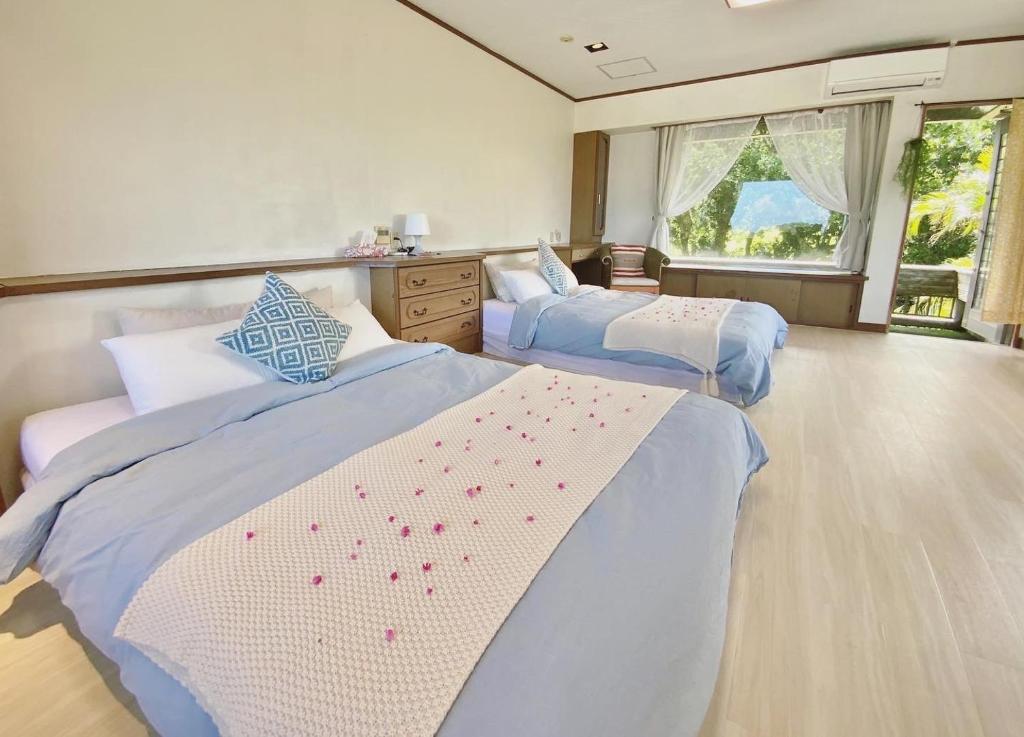 石垣岛イリワ -stay&coffee iriwa-的一间卧室设有两张床和窗户。