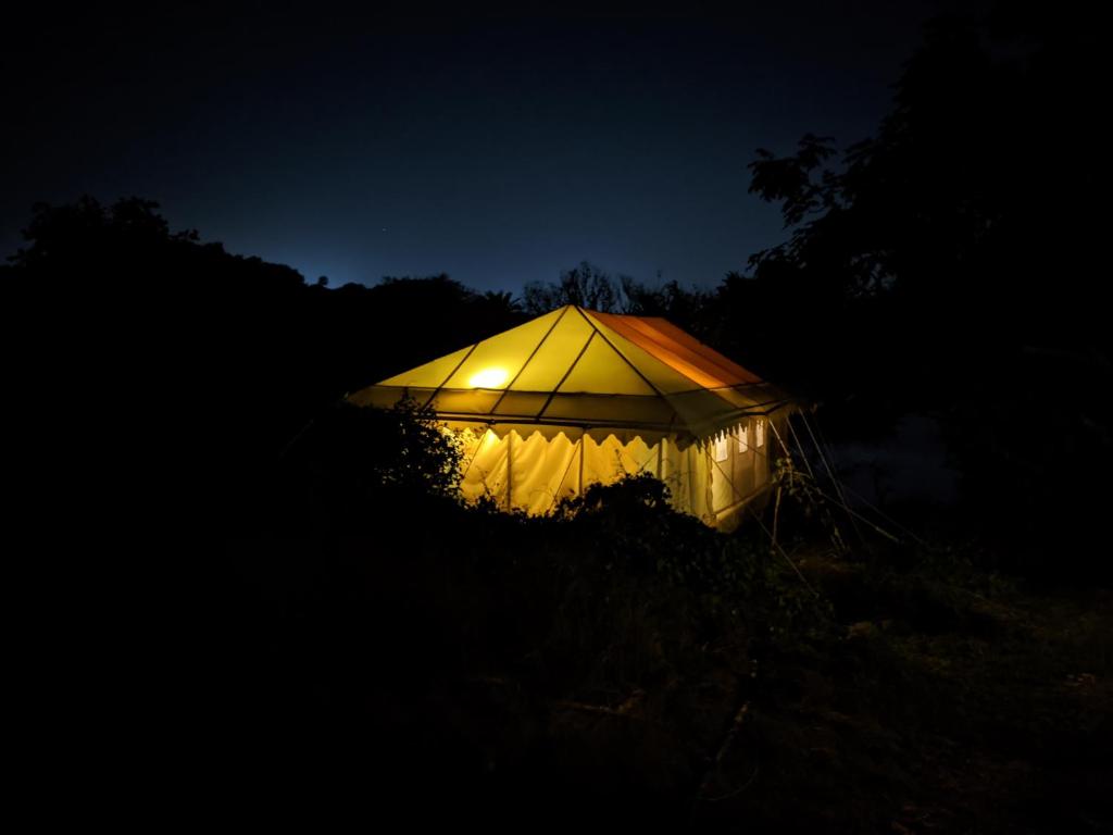 乌代浦Dera Baghdarrah Nature Retreat Udaipur的夜晚在黑暗中点燃的帐篷