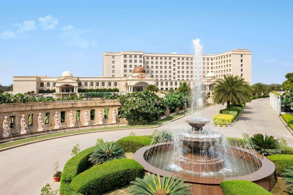 勒克瑙Ramada by Wyndham Lucknow Hotel and Convention Center的建筑物前公园的喷泉
