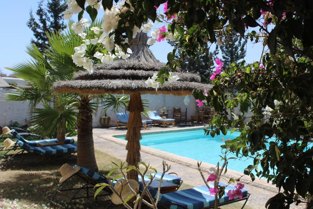 索维拉Riad Sanam essaouira的一个带游泳池、遮阳伞和椅子的度假村