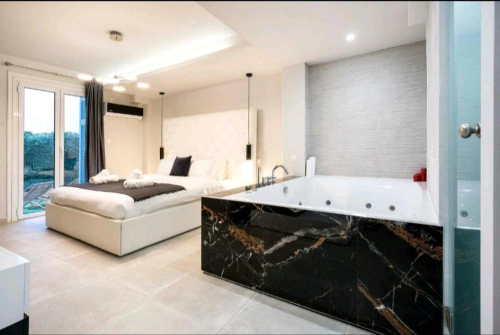 雅典DELUXE ROMANTIC JACUZZI的一间带浴缸的浴室和一张位于客房内的床