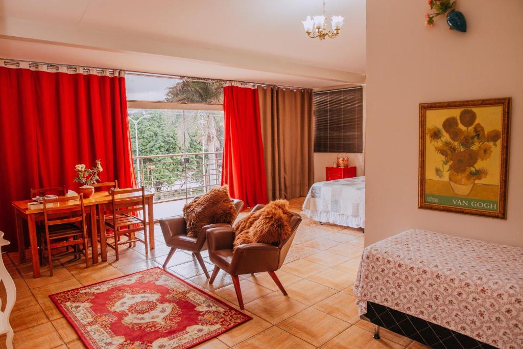 伊通比亚拉贝拉里约宾馆的客厅配有红色窗帘和桌椅