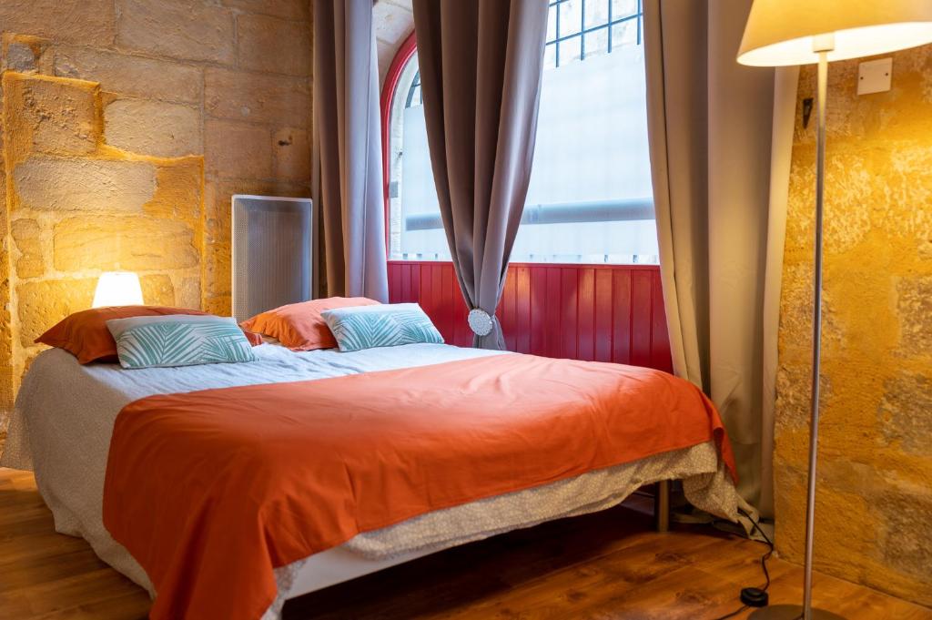 佩里格Le Logis du puy ST FRONT gite urbain PÉRIGUEUX的一间卧室配有带橙色床单的床和窗户。