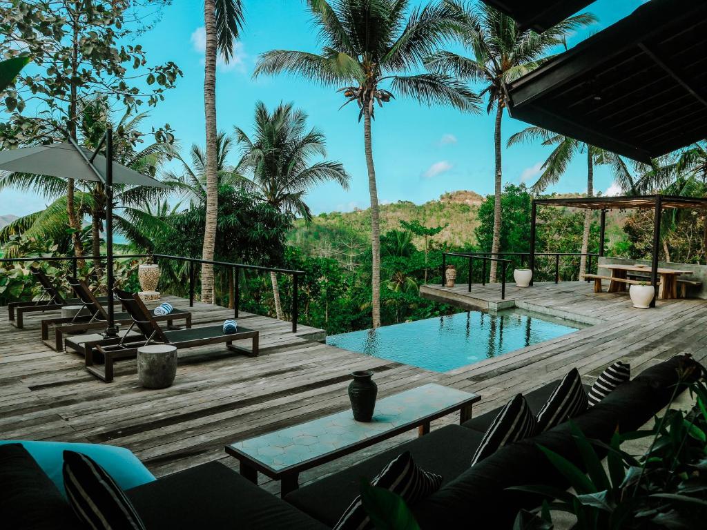 塞隆贝拉纳克Villa Kanan, Secluded Jungle Paradise的一个带游泳池、椅子和棕榈树的度假村