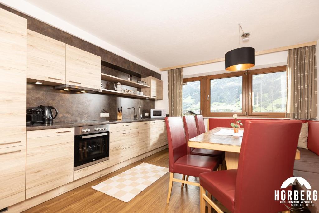 施文道HORBERG Appartements的厨房配有木桌和红色椅子
