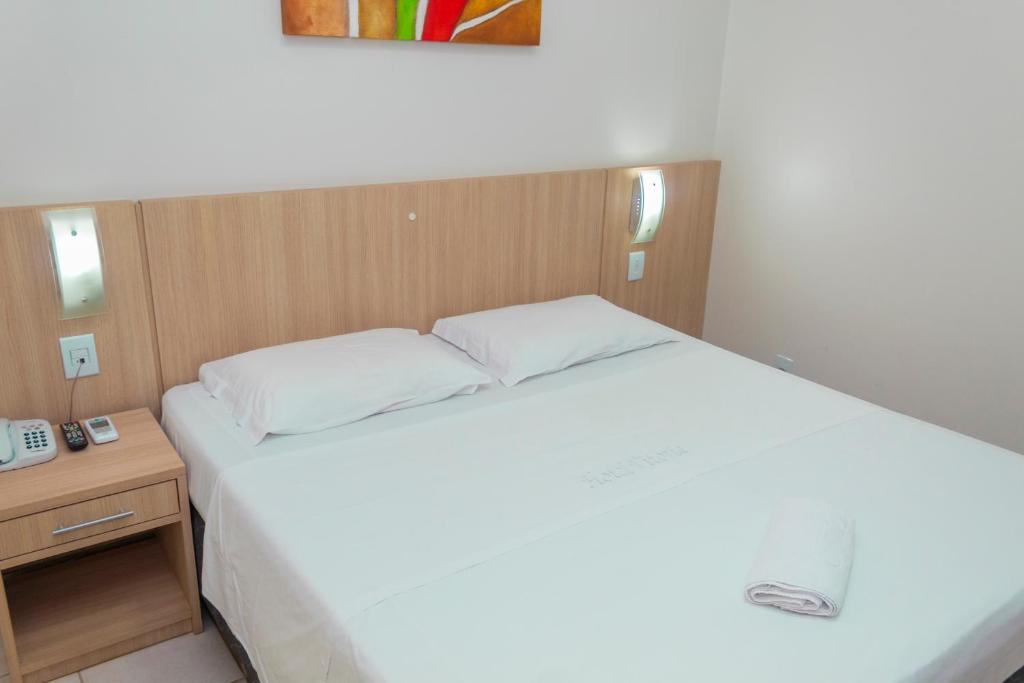 伊达贾伊Hotel Vitoria - Itajaí的卧室配有白色大床和电话