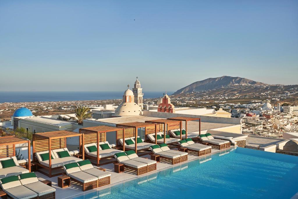 费拉Katikies Garden Santorini - The Leading Hotels Of The World的一个带躺椅的游泳池,享有城市美景