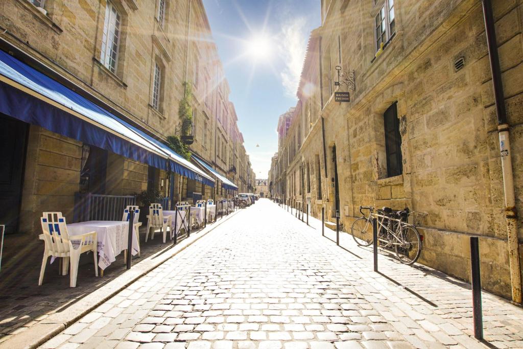 波尔多Maison Fredon Bordeaux Centre的一条鹅卵石街道,在一条小巷里摆放着桌椅