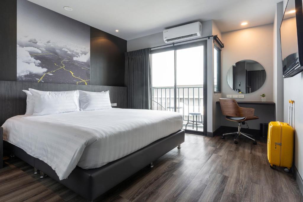 清迈Sleep Mai Chiang Mai Airport Lifestyle Hotel - SHA Plus的一间卧室配有一张床和一张带黄色手提箱的书桌