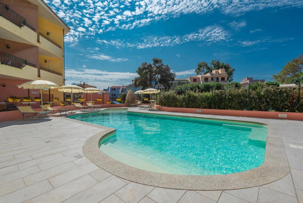 圣特雷莎加卢拉伊米尔缇比安奇住宅酒店的一座带椅子和遮阳伞的游泳池位于一座建筑旁边