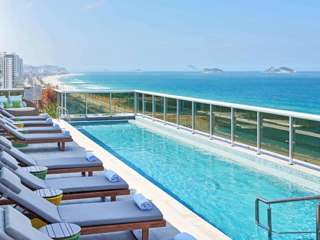里约热内卢里约热内卢巴拉达蒂茹卡酒店的一个带躺椅的游泳池和大海