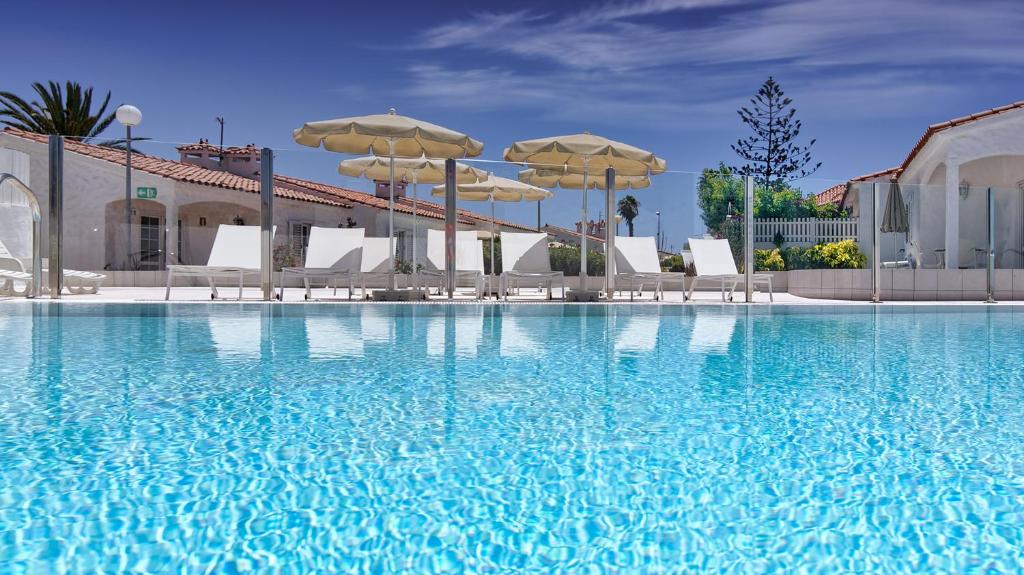 英格兰海滩阿多尼斯别墅酒店的一个带遮阳伞和椅子的大型游泳池