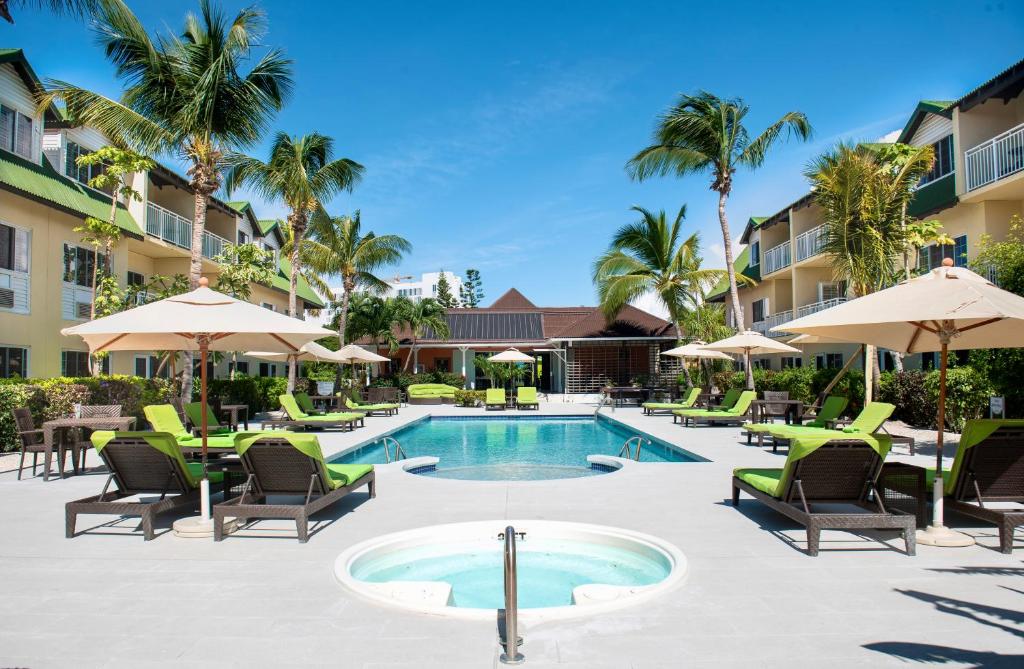格雷斯湾卡尔港康福特套房度假酒店的度假村的游泳池配有椅子和遮阳伞