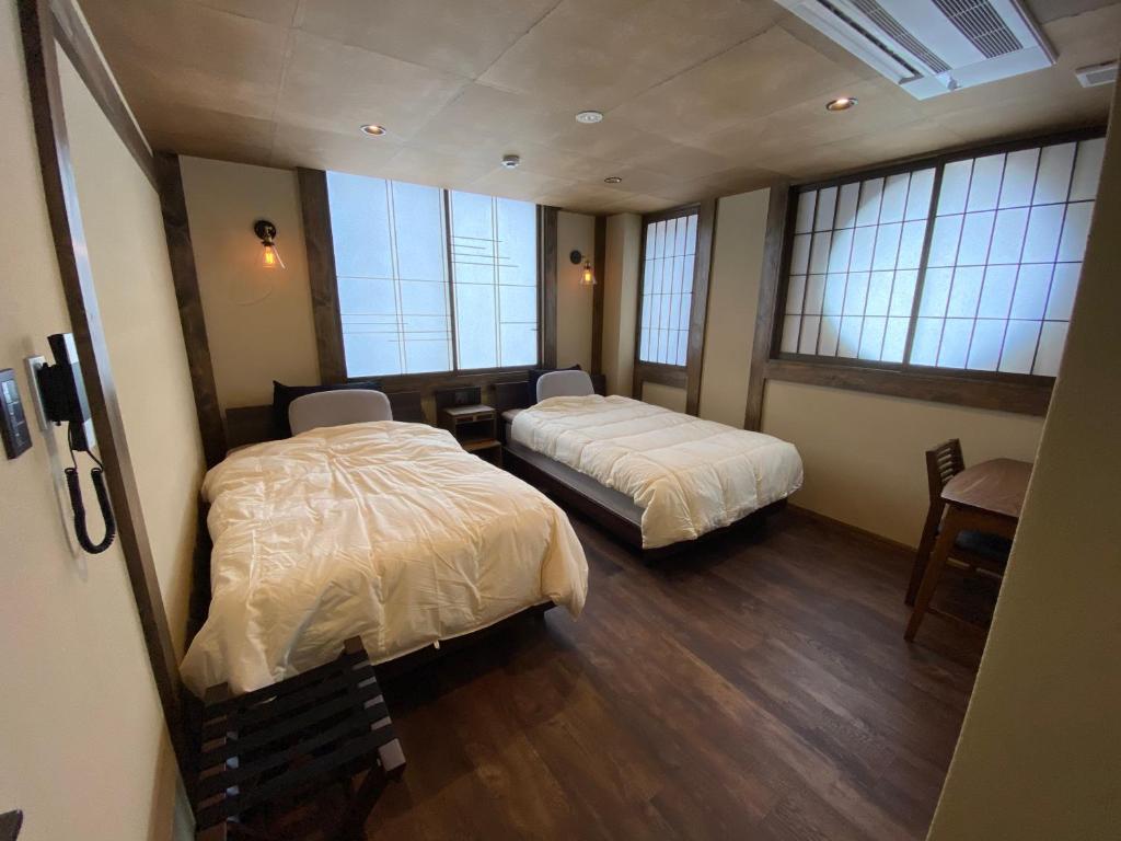 金泽日月庵 BnB Sunmoon的带窗户的客房内的两张床