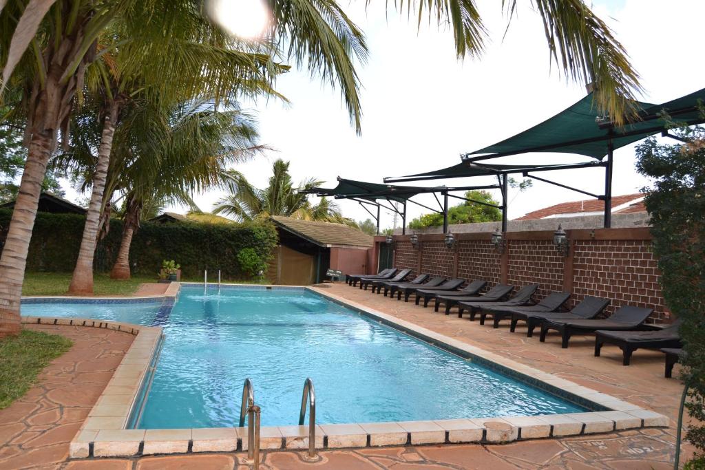 VoiImpala Safari Lodge的一个带躺椅的游泳池,棕榈树
