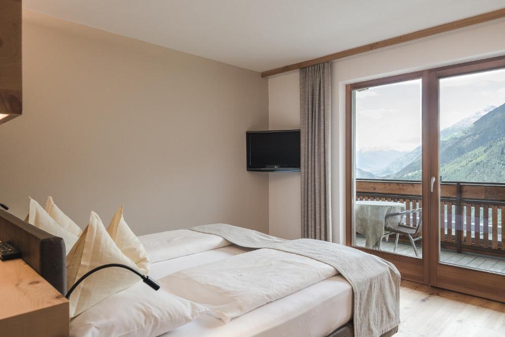 思科纳Naturhotel Gruberhof的酒店客房设有一张床和一个阳台。