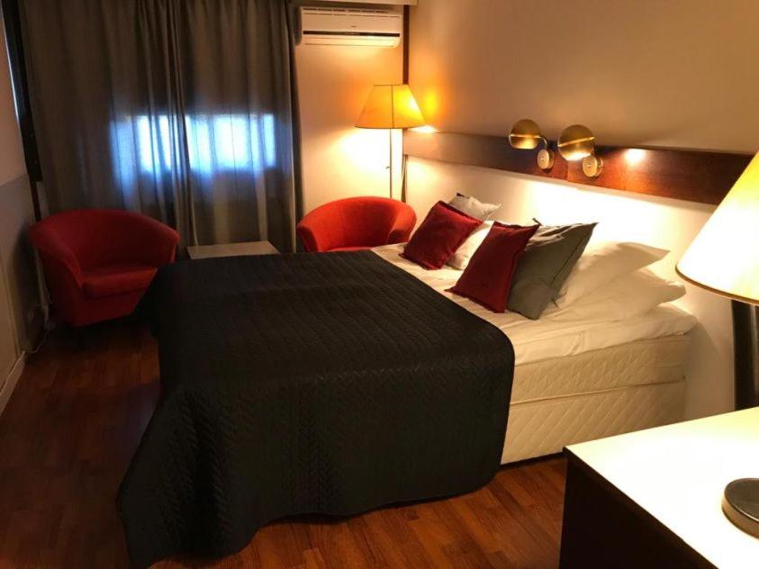 SuonenjokiHotel Carneval的酒店客房,配有一张床和一张红色椅子
