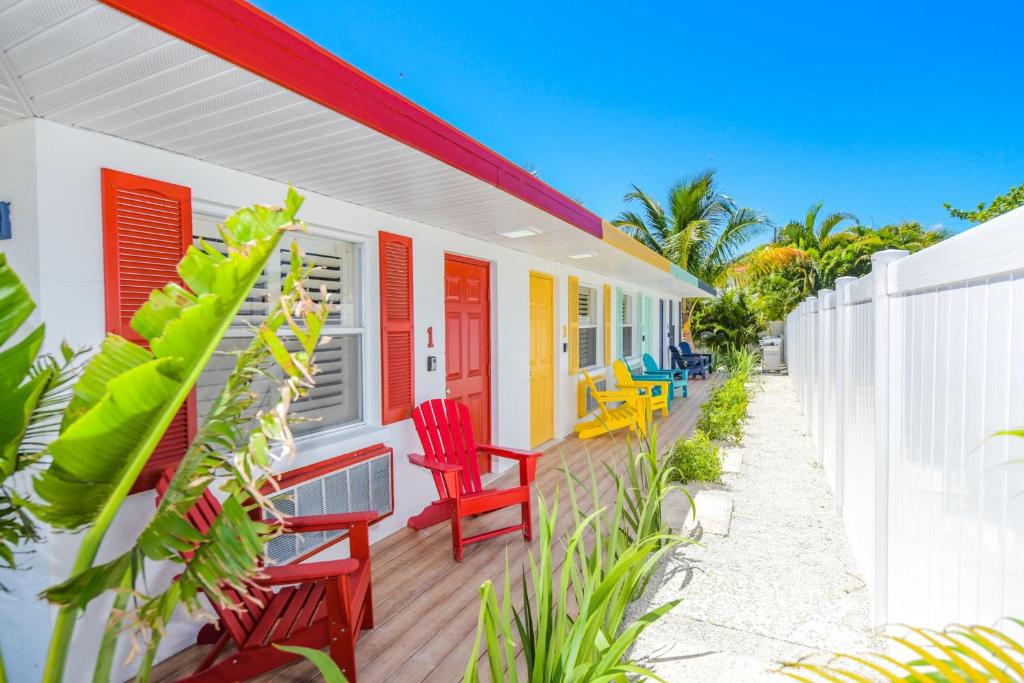 布雷登顿海滩Captain’s Quarters at Anna Maria Island Inn的色彩缤纷的房屋,甲板上摆放着红色椅子