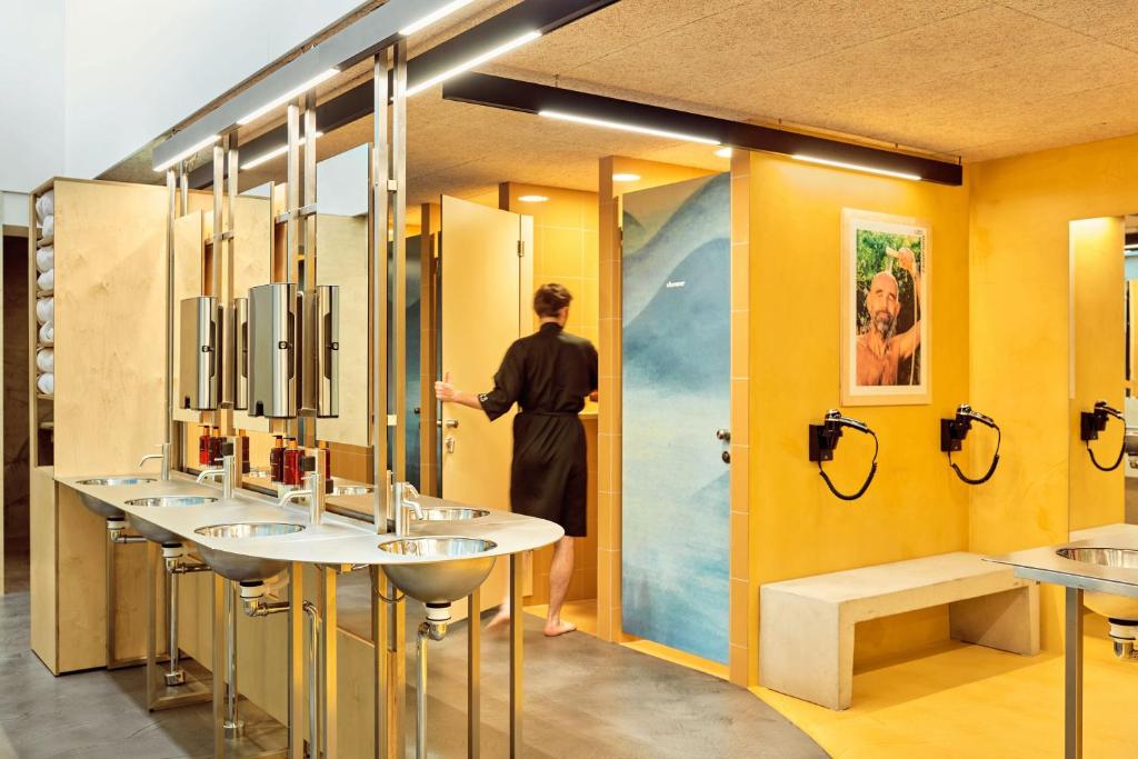 哥本哈根CityHub Copenhagen的站在带四个水槽的浴室中的女人