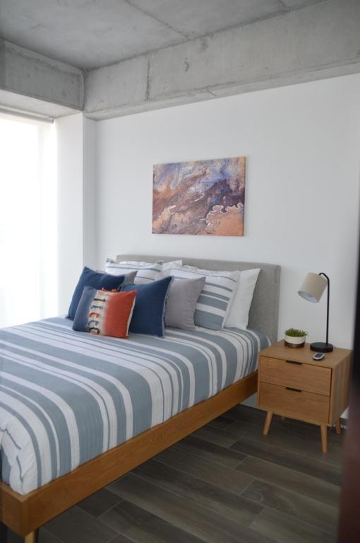危地马拉Cozy Stays Cayala Apartments 3的一间卧室配有一张带蓝色和白色枕头的床