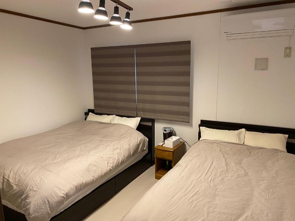 宫古岛L House Miyako Island的一间卧室设有两张床和窗户。