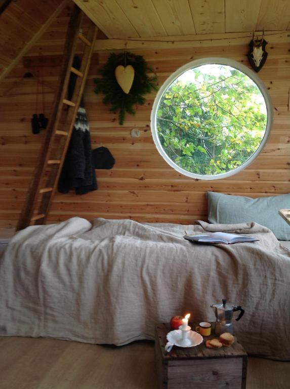 KværndrupTreehouse escape的一间卧室设有一张床和一个圆形的窗户。
