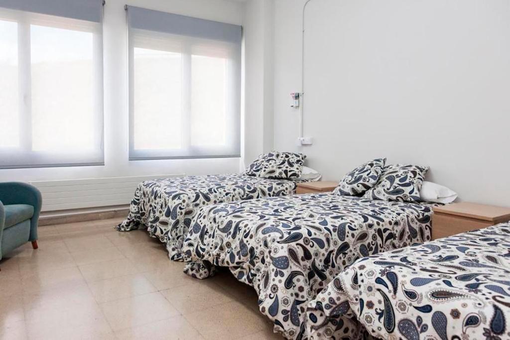 哈卡Residencia Albergue Jaca的客房设有两张床、一张沙发和窗户。