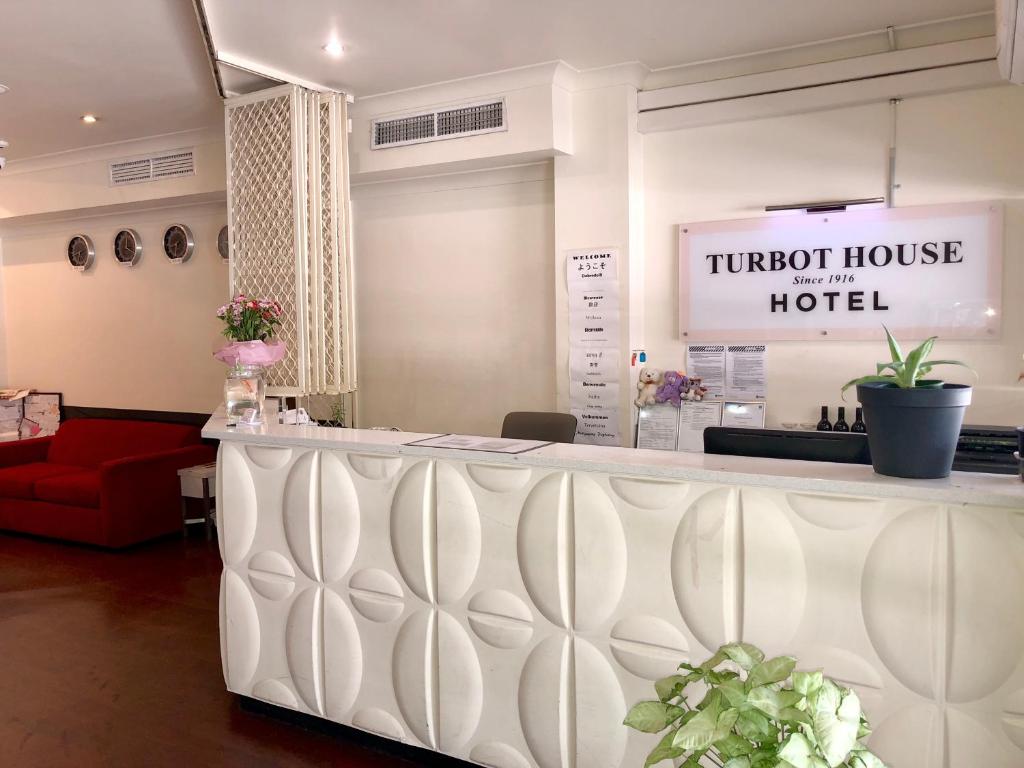 布里斯班Turbot House Hotel的酒店大堂设有柜台和红色沙发