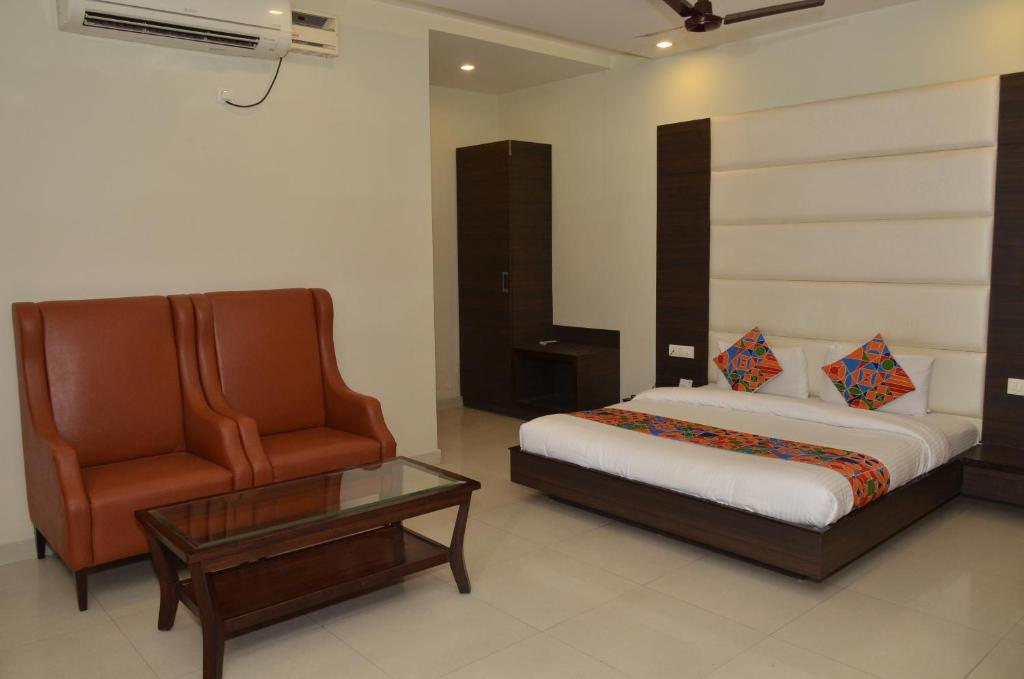 阿姆利则Hotel KK Continental 50 Meter from Railway Station - Amritsar的一间卧室配有一张床、一把椅子和一张桌子
