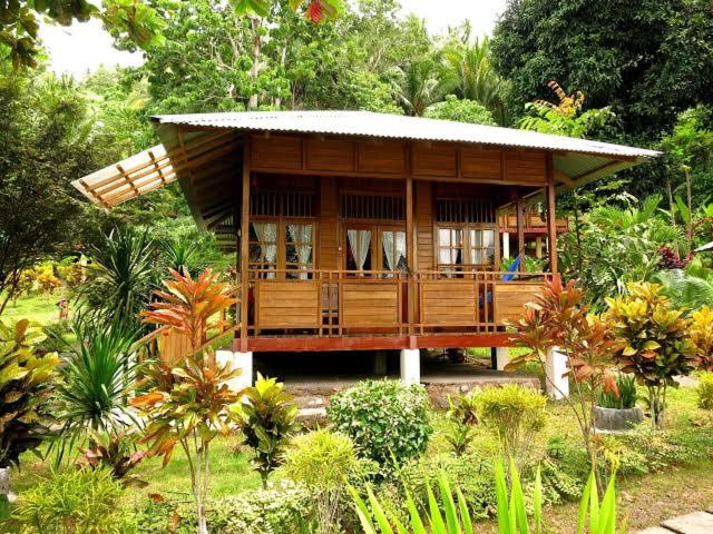 BitungTwo Fish Resort Lembeh的一座小木房子,位于种有树木的花园内