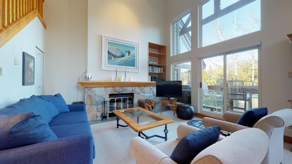 惠斯勒Lush Forest and Golf Course Views by Harmony Whistler的客厅设有蓝色的沙发和壁炉
