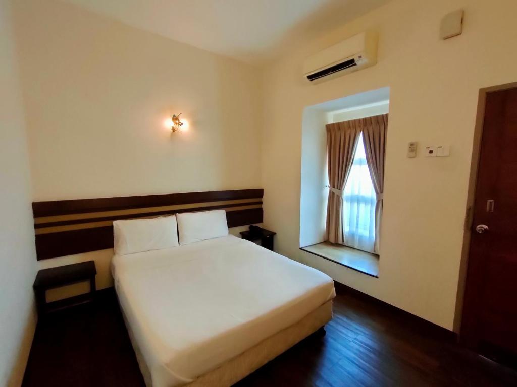 马六甲Cozzy Motel的卧室配有白色的床和窗户。