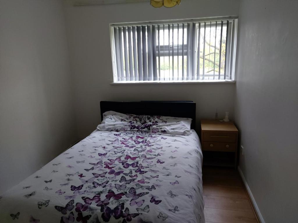 罗姆福特Relaxing double bedroom的一间卧室配有一张带花卉棉被的床和窗户。