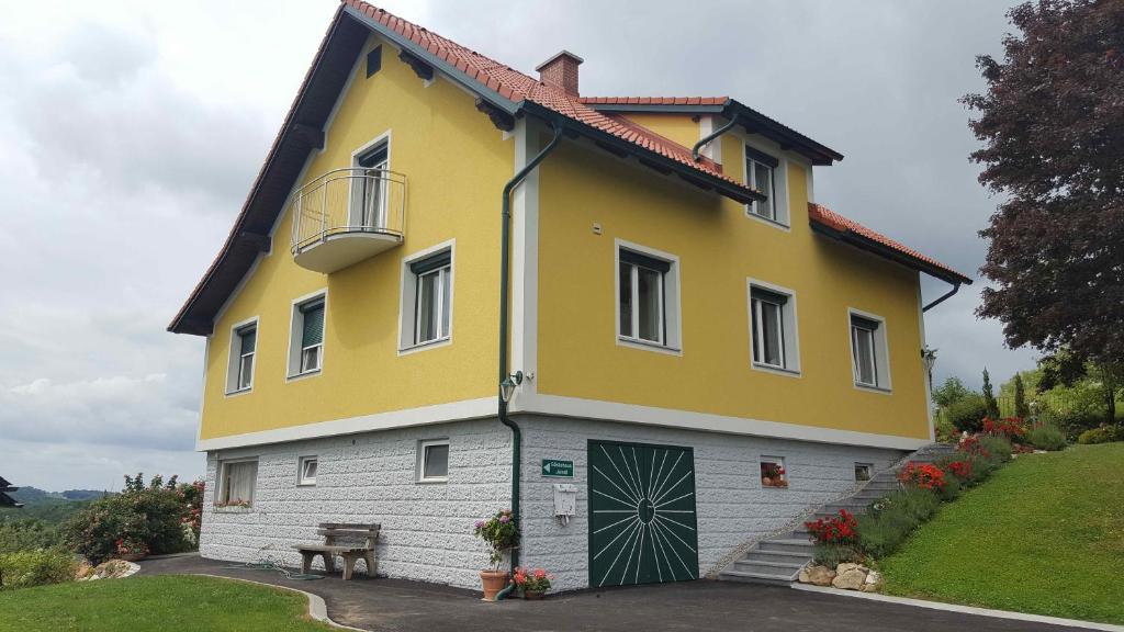 HartmannsdorfGästehaus Jeindl的黄色和白色的房子,前面有长凳