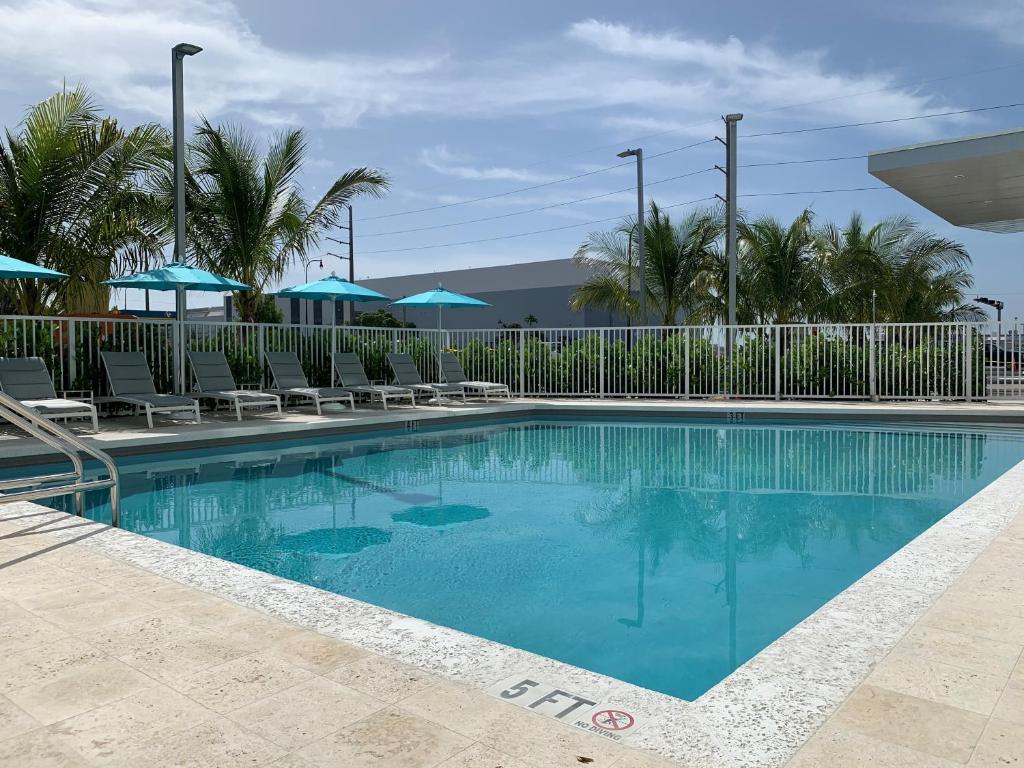 迈阿密Wyndham Garden Miami International Airport的度假村的游泳池，配有椅子和遮阳伞