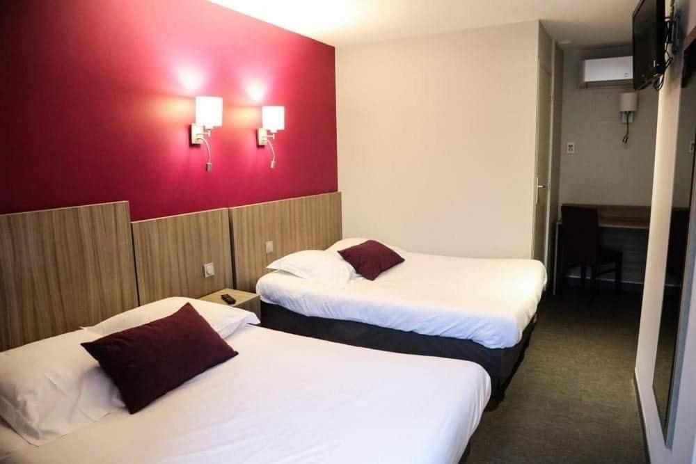 拉沙特尔HOTEL DU COMMERCE的酒店客房设有两张床和红色的墙壁。