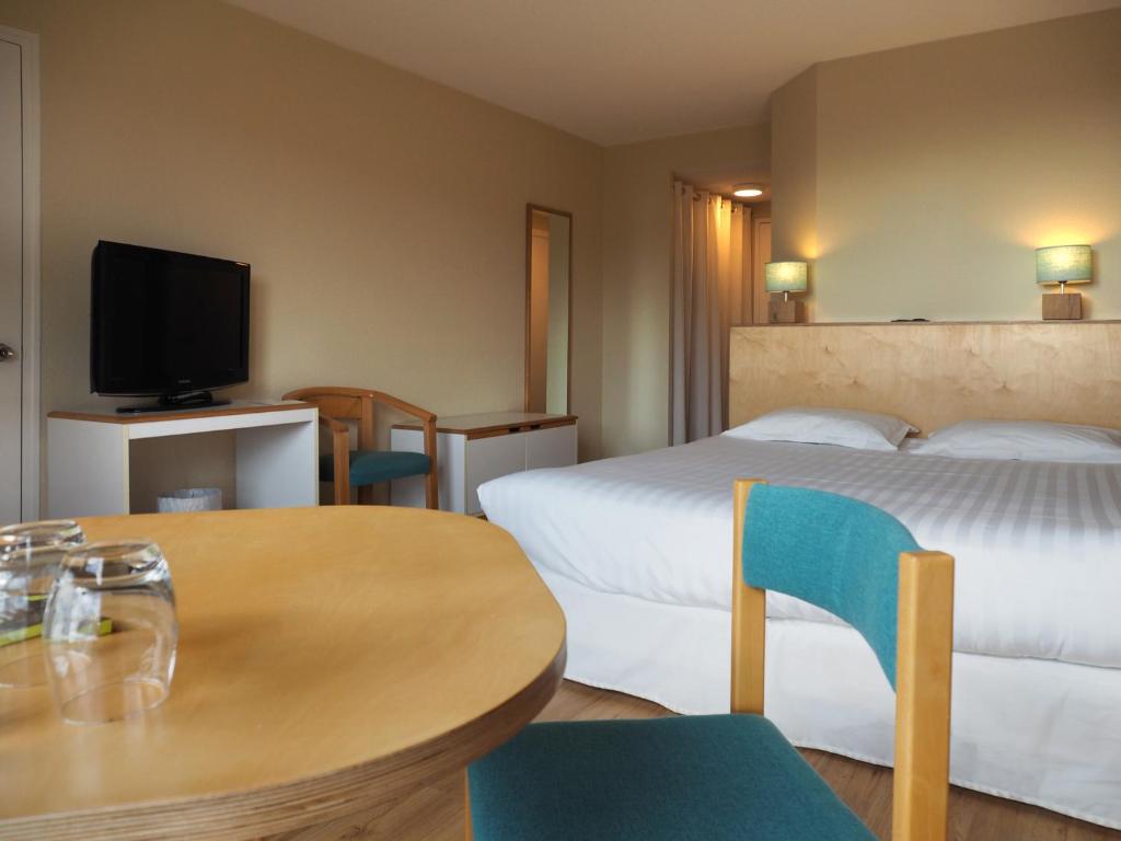 布雷斯特Logis Hôtel du Belvédère的酒店客房带两张床和一张桌子以及椅子。