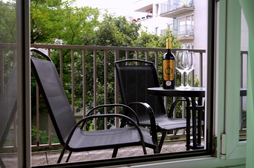 布拉格apartment golden Prague的阳台上配有一张桌子、一瓶葡萄酒和两把椅子