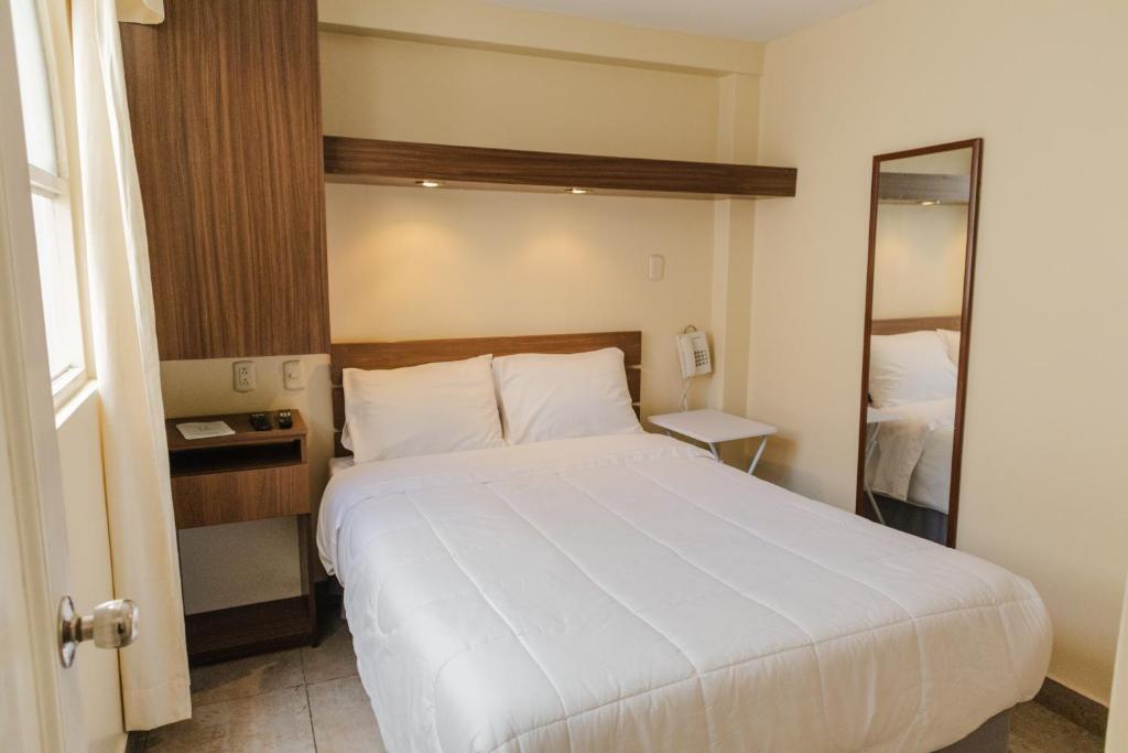 利马Hotel Residencial Alfa的卧室配有一张白色大床和镜子