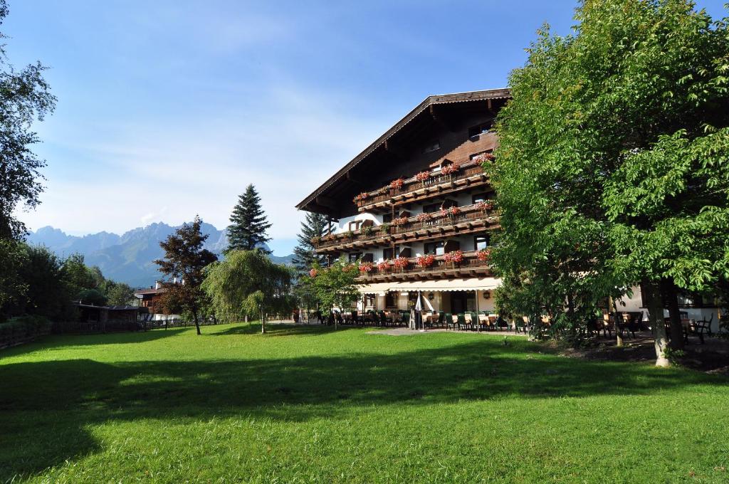蒂罗尔州奥伯恩多夫基茨比厄尔阿尔卑斯山国王酒店的前面有绿色草坪的大建筑